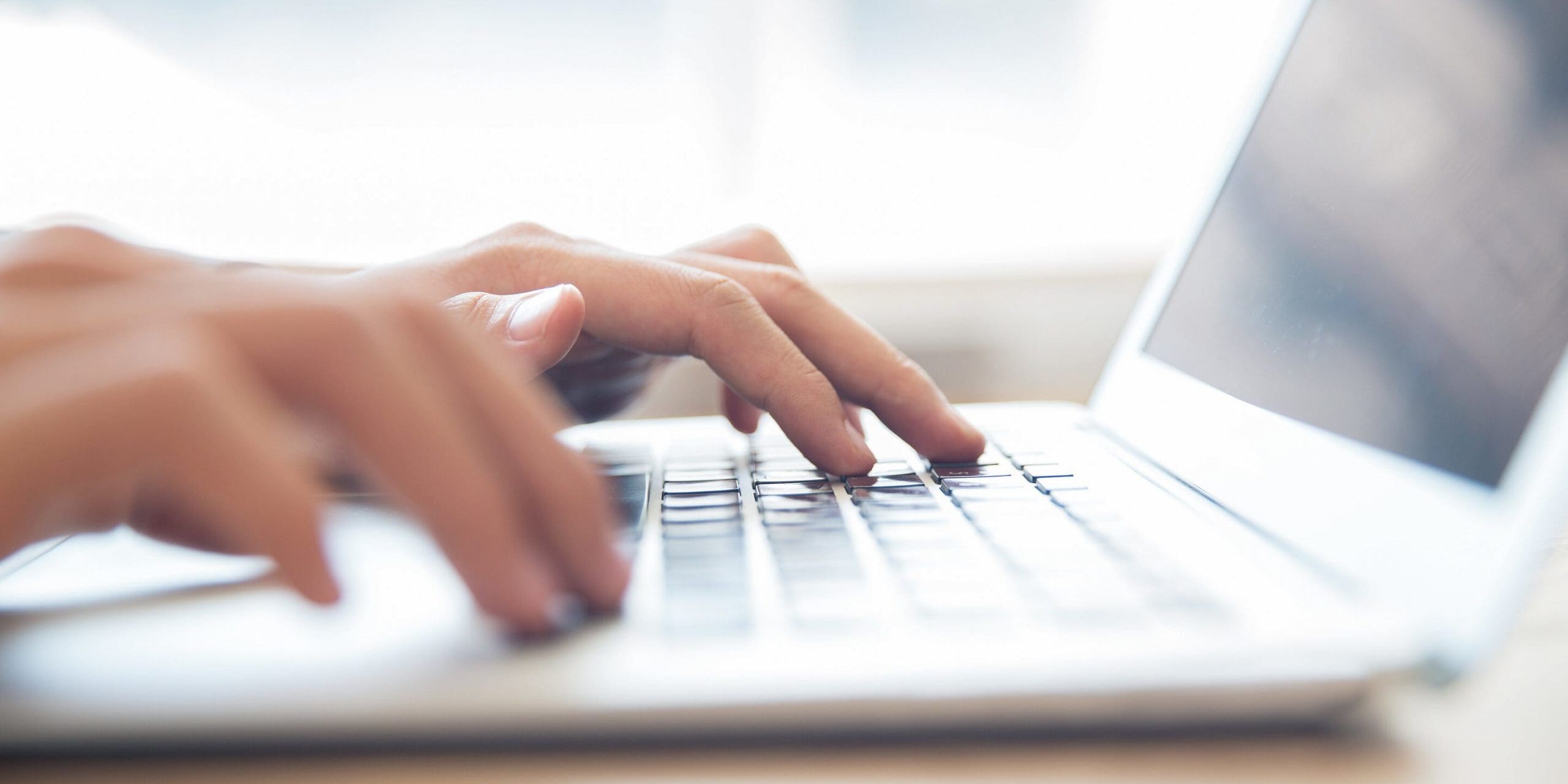 Close-up of male hands typing on laptop keyboard indoors. Businessman working in office or student browsing information